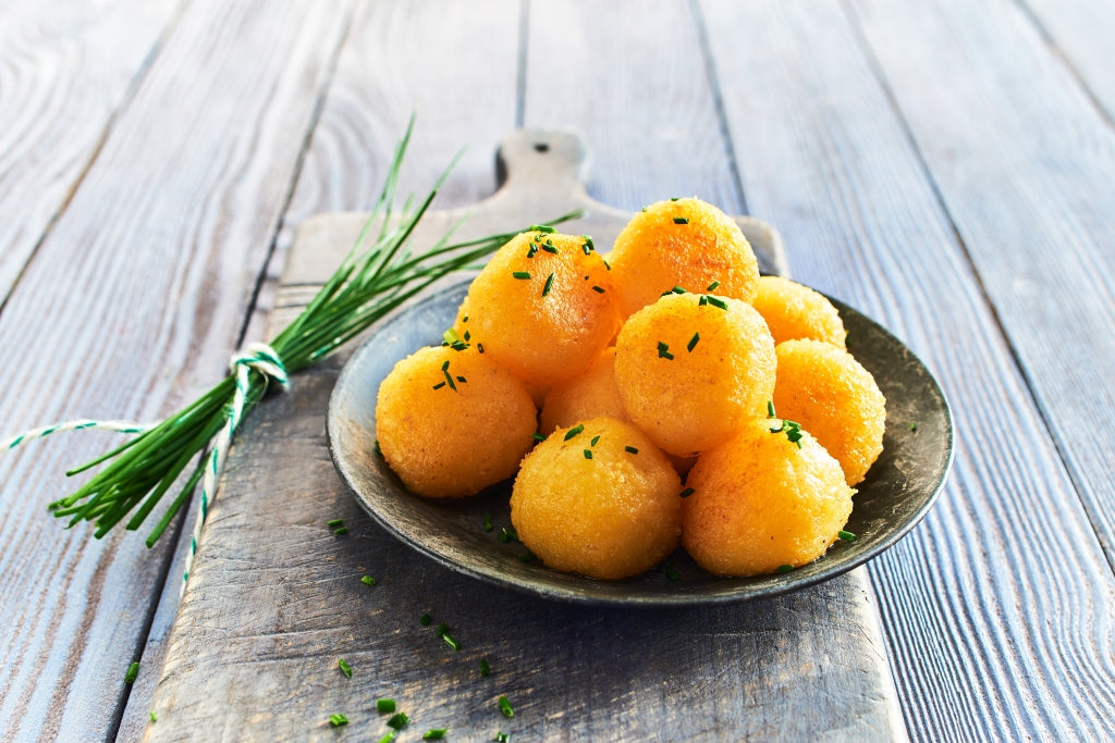 Kartoffelklöße angerichtet auf einem Teller, dazu ein Bündel Schnittlauch